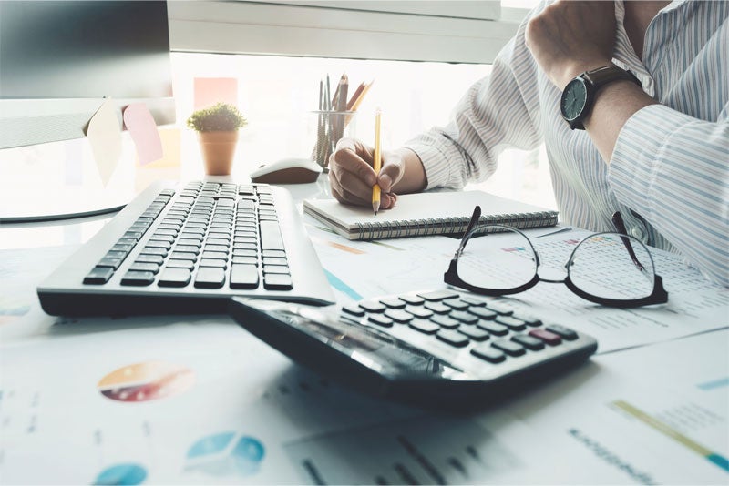 A person sitting at a desk with a pencil in hand.